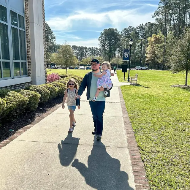 A father walks with his two daughters across the USCB campus on a Sunday morning