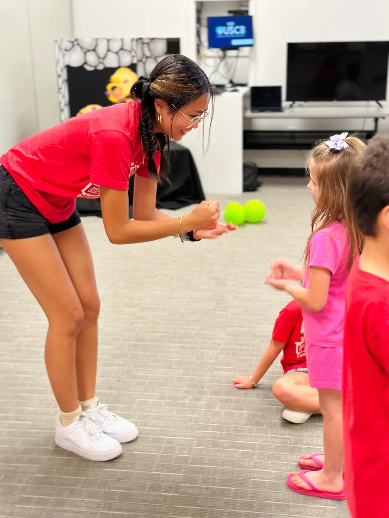 A Bridge Kids volunteer leading young children in a floor circle activity