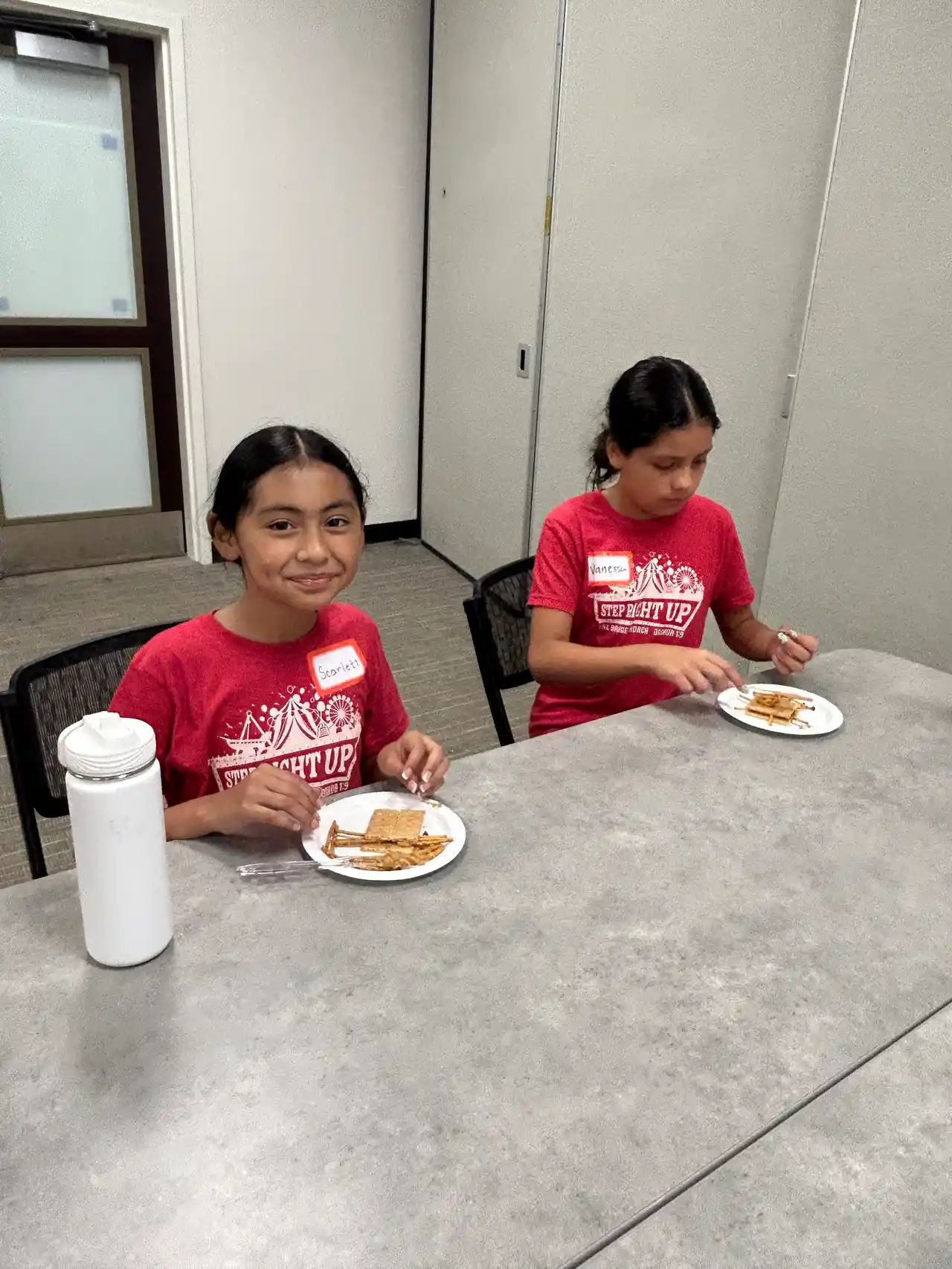 A VBS volunteer helping a young camper at the registration and treats table