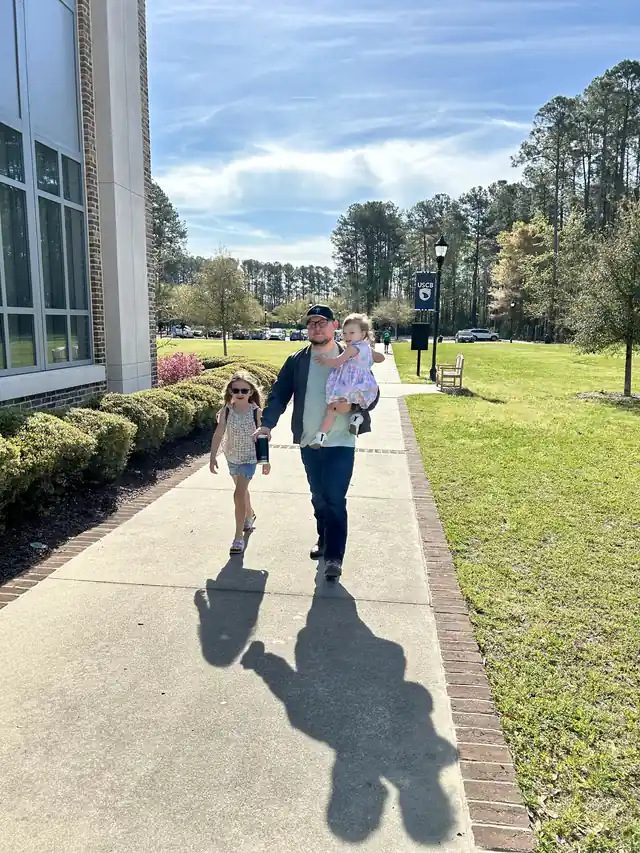 A family walking up the sunny sidewalk to Sunday service at the USCB campus
